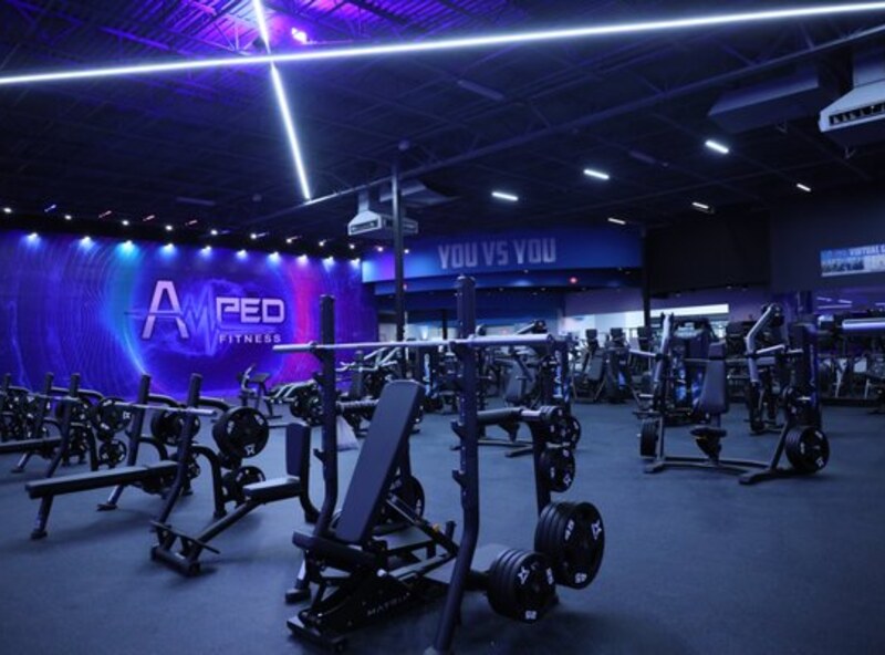 Amped Fitness training floor with strength equipment and illuminated branding.