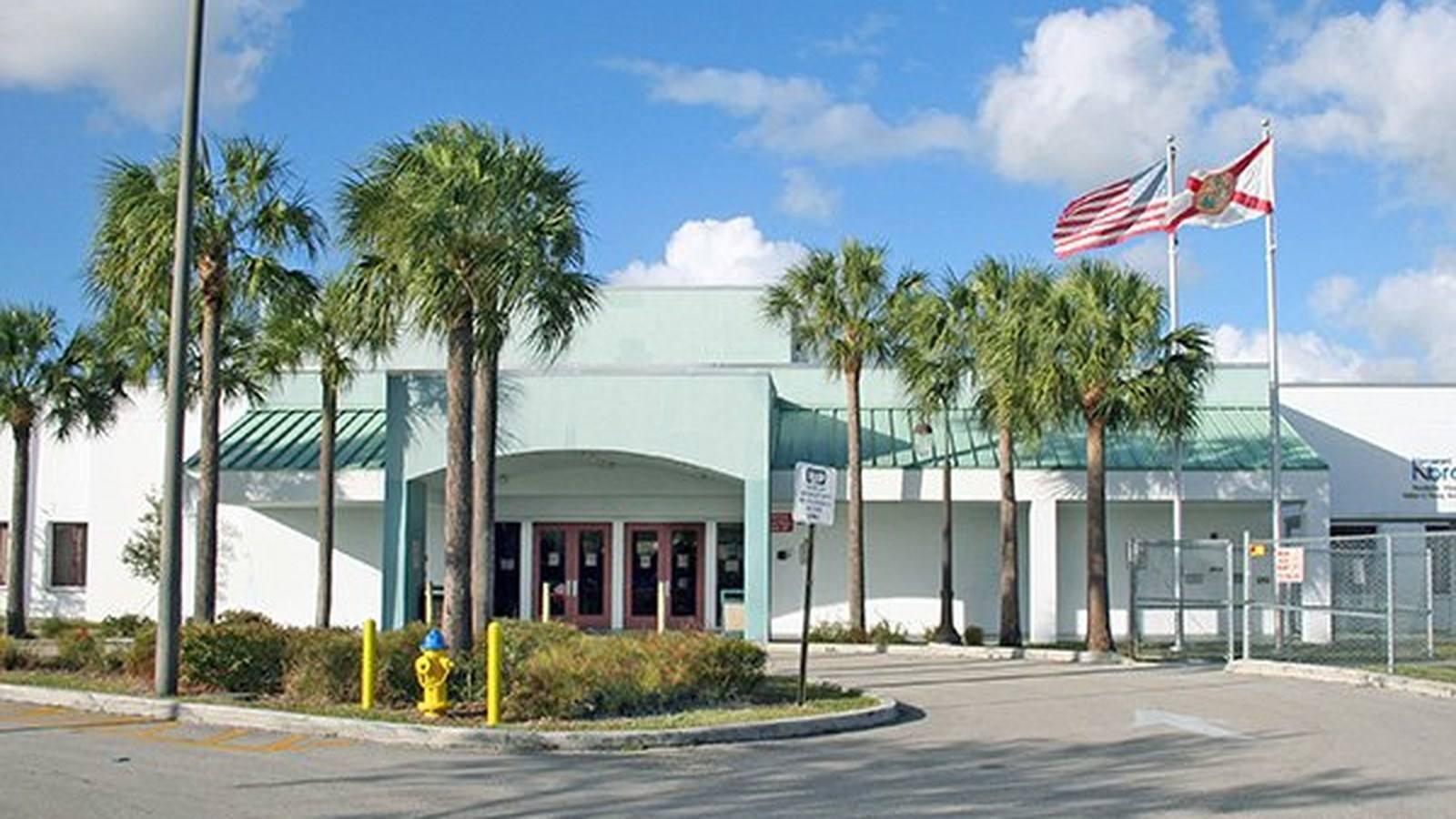 Exterior of the Pembroke Pines / Walter C. Young Resource Center with American and Florida flags and palm trees in Pembroke Pines, Florida