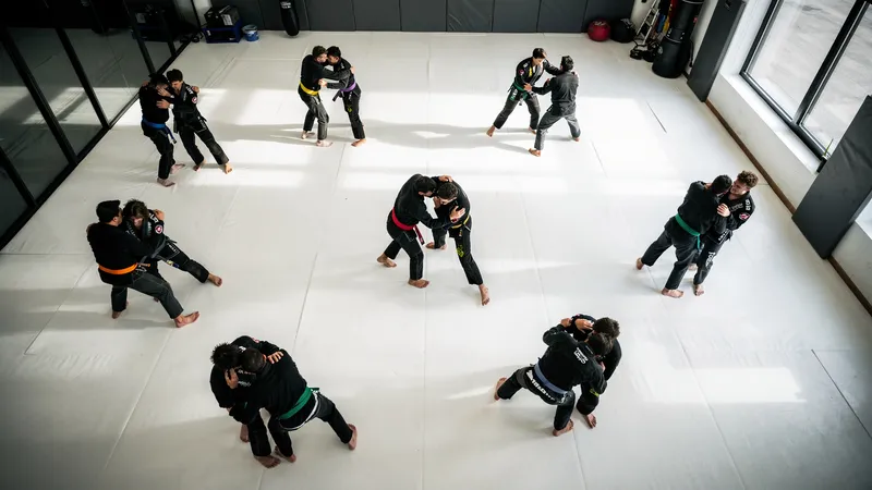 Youth Brazilian jiu-jitsu students training on white mats under instructor supervision
