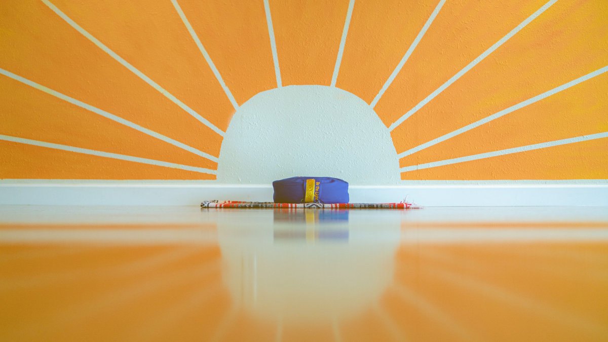 Lighthouse Yoga & Wellness — meditation corner with an orange sunburst mural, cushion and mats (photo from the studio's official website)