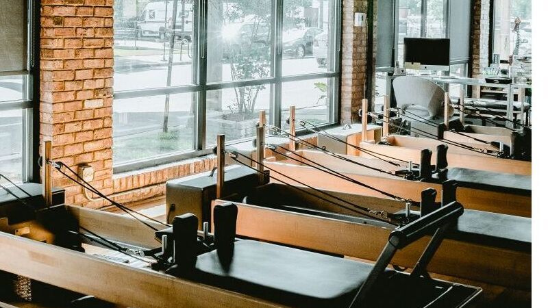 Bright modern Pilates studio interior with reformer equipment and natural light — editorial representative image